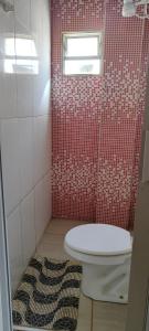 baño con aseo y pared de azulejos rojos en Kitnet mobiliada, quarto, banheiro, cozinha americana, en Luziânia