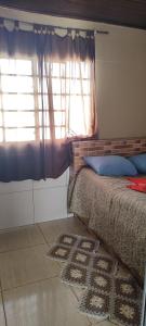 1 dormitorio con cama, ventana y alfombra en Kitnet mobiliada, quarto, banheiro, cozinha americana, en Luziânia