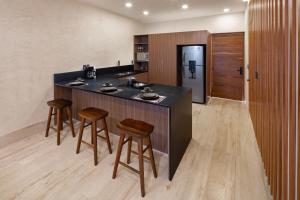 a kitchen with a black counter and two stools at Bunah Tulum -Distinctive Hotels- in Tulum
