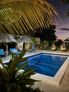 a swimming pool with chairs and an umbrella at Hotel Tranquilo in Las Peñitas