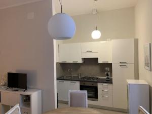 a kitchen with white cabinets and a table and chairs at "le Volte" Appartamento nel cuore di Foligno in Foligno