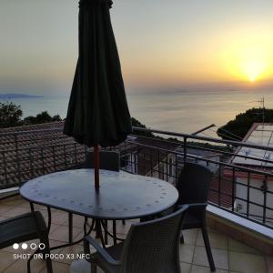 - une table avec un parasol sur le balcon offrant une vue sur le coucher du soleil dans l'établissement B&B Vista Mare con Terrazzo, à Palmi