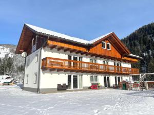a house in the snow with a balcony on it at Ferienwohnungen zum Klammlhof in Ebene Reichenau