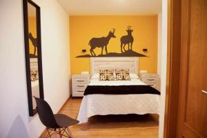 Schlafzimmer mit einem Bett mit Hirsch an der Wand in der Unterkunft Cumbres De Los Picos Apartamento Rebecos in Poo de Cabrales