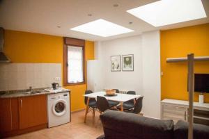 a kitchen with a table and a washing machine at Cumbres De Los Picos Apartamento "Rebecos" in Poo de Cabrales