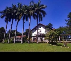 a group of palm trees in front of a house at Ninho dos Passaros Penedo RJ in Penedo