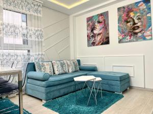uma sala de estar com um sofá azul e um quadro em Apartmani SLEEP&JOY em Zlatibor