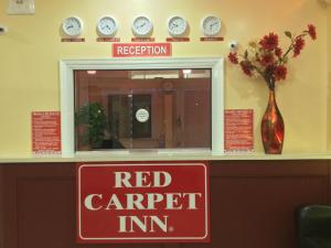 un cartel de alfombra roja en un mostrador con relojes en Red Carpet Inn-Bridgeton/Vineland, en Bridgeton