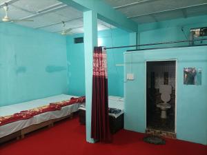 a room with two beds and a bathroom with a toilet at Shri Gamya Guest House in Ujjain