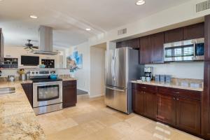 a kitchen with wooden cabinets and a stainless steel refrigerator at Sonoran Sunshine by AvantStay Pool Putting Green BBQ Ping Pong Pool Table Entertainers Wonderland in Scottsdale
