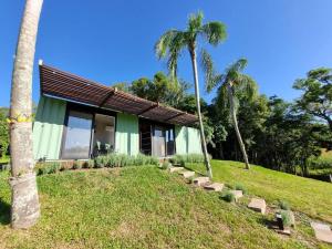 a green building with palm trees in front of it at TinyWine House Vale dos Vinhedos - Cabana Chardonnay in Garibaldi
