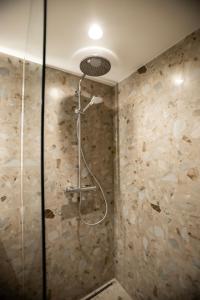 a shower in a bathroom with a stone wall at Loft 27 in Kaunas
