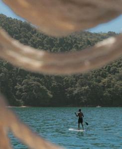 a man standing on a paddle board in the water at Nômades Adventure Hostel & Coworking in Florianópolis