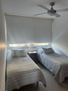 a bedroom with two beds and a ceiling fan at Edificio Calypso - Primera línea al Mar in Punta del Este