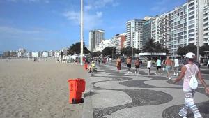 un grupo de personas caminando por la playa en Flat Copacabana quadra da praia 907, en Río de Janeiro