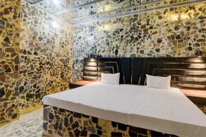 een slaapkamer met een bed in een kamer met stenen muren bij Super OYO A.S.Castle in Kākori