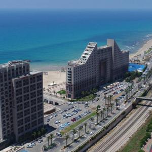 een luchtzicht op een gebouw en een parkeerplaats met auto's bij Almog Tower in Haifa