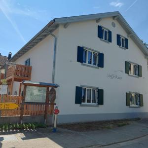 een wit gebouw met blauwe ramen en een bord bij Stoffelbauer in Pappenheim