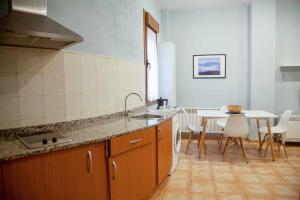 cocina con fregadero y mesa con sillas en Cumbres de los Picos Apartamento Urriellu, en Poo de Cabrales