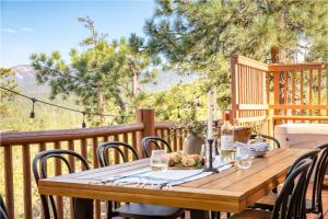 une table et des chaises en bois sur une terrasse avec des arbres dans l'établissement Tanglewood by AvantStay 10mins to Bear Mountain Contemporary Hillside Cabin, à Big Bear Lake