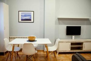 una sala da pranzo bianca con tavolo e TV di Cumbres de los Picos Apartamento Urriellu a Poo de Cabrales