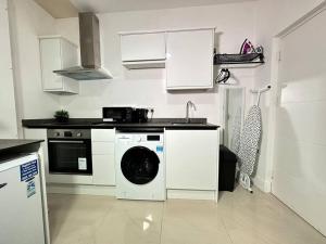a kitchen with a washing machine and a sink at Charming & Cosy Studio Retreat in Kidderminster in Kidderminster