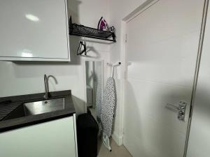 a small white kitchen with a sink and a door at Charming & Cosy Studio Retreat in Kidderminster in Kidderminster