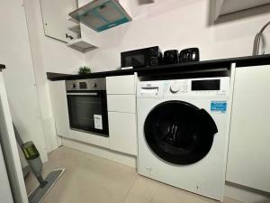 eine Küche mit einer Waschmaschine und einer Mikrowelle in der Unterkunft Charming & Cosy Studio Retreat in Kidderminster in Kidderminster