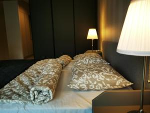 uma cama com duas almofadas ao lado de um candeeiro em Apolonia apartamenty I - SPA em Dziwnów