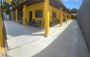um edifício amarelo com cadeiras num pátio em Casa de Praia na Barra de São Miguel - AL na Barra de São Miguel