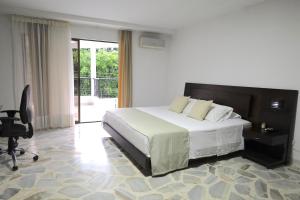 a bedroom with a bed and a desk and a chair at Babilla Suites in Cali