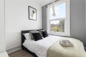 Schlafzimmer mit einem weißen Bett und einem Fenster in der Unterkunft Cosy 3 Bed Flat 15mins to Kings Cross in London