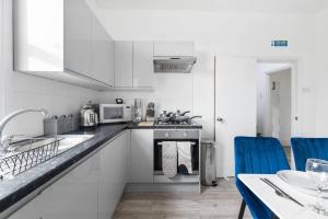 a kitchen with white appliances and a table with blue chairs at Cosy 3 Bed Flat 15mins to Kings Cross in London