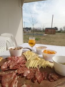 einen Tisch mit Fleisch und Käse sowie ein Glas Wein in der Unterkunft Quintas La escondida in Chivilcoy