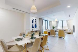 a dining room and living room with a table and chairs at Janayen Avenue - Locations in Dubai