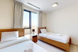 a bedroom with two beds and a window at Janayen Avenue - Locations in Dubai