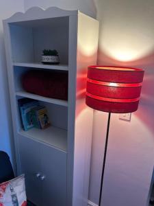 una lámpara roja sentada junto a un estante de libros en Airport Retreat en Handforth
