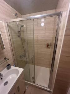 a shower with a glass door next to a sink at Airport Retreat in Handforth