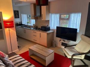 a living room with a television and a kitchen at Airport Retreat in Handforth