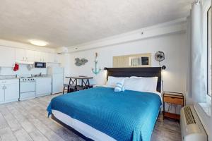 a bedroom with a blue bed and a kitchen at Harbour Beach Resort 618 in Daytona Beach