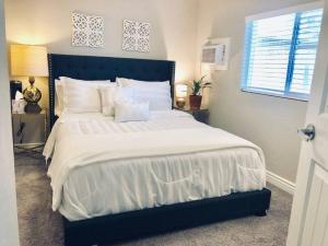 a bedroom with a large bed with white sheets and a window at Sunny Guest Suite with large backyard - Pets Welcome in Phoenix