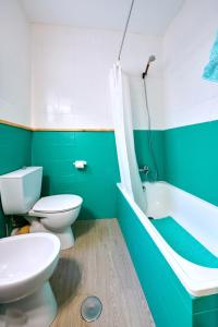 - une salle de bains verte et blanche avec des toilettes et une baignoire dans l'établissement Amplio piso en zona céntrica de Baena, à Baena