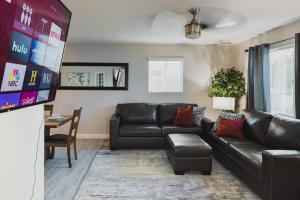 a living room with a black leather couch and a table at Modern 3BR,2BA with Game Hallway - Pets Welcome in Phoenix