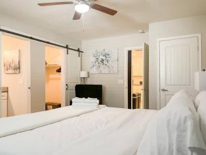 a bedroom with a large white bed with a ceiling fan at Modern 3BR,2BA with Game Hallway - Pets Welcome in Phoenix