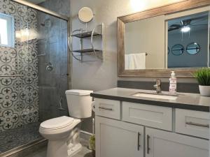 a bathroom with a toilet and a shower with a mirror at Modern 3BR,2BA with Game Hallway - Pets Welcome in Phoenix +30 photos