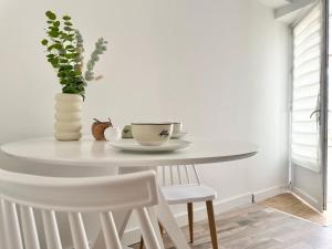 a white dining room table with a vase and chairs at Logement Entier au Centre Ville in Évreux +16 photos