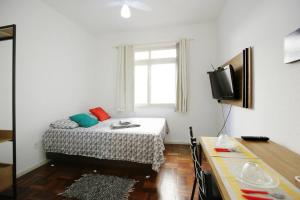 a small bedroom with a bed and a television at Apto Centro Histórico ótima localização e iluminado in Porto Alegre