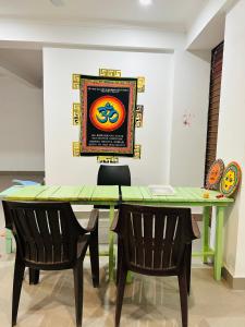 a dining room table with two chairs and a painting on the wall at wuiD stayin wakeupinDoon in Dehradun