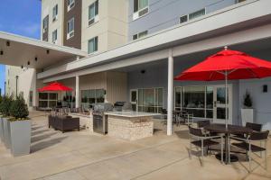 a patio with a table and chairs and red umbrellas at TownePlace by Marriott Suites Clarksville in Clarksville