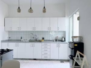 a white kitchen with white cabinets and a black refrigerator at Sunny Eclectic 3BR house in Gemmayze in Beirut